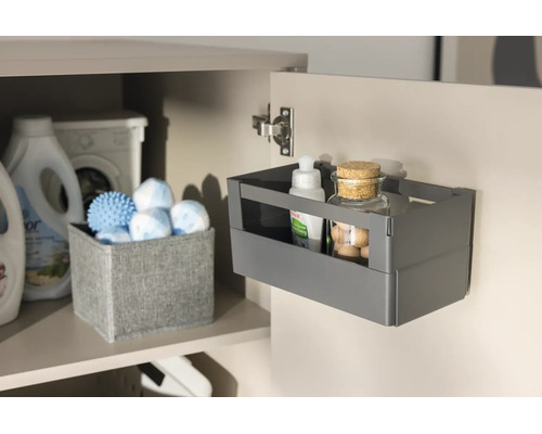 Organisateur gris fixé à l'intérieur d'une porte de placard pour ranger des produits de nettoyage.