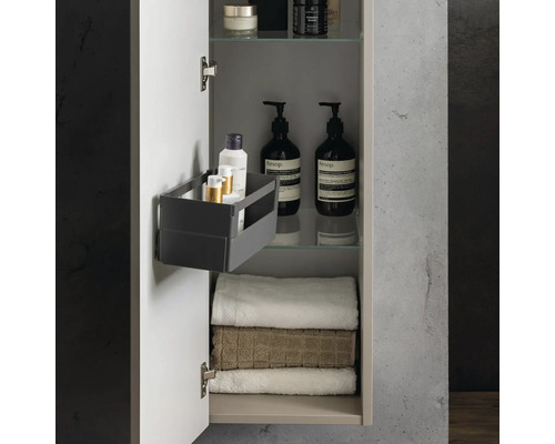 Armoire de toilette ouverte avec serviettes, flacons de cosmétiques sur des étagères en verre et une boîte de rangement sur la porte.