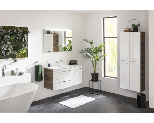 Salle de bains moderne et lumineuse avec meuble sous-vasque blanc, armoire haute suspendue, baignoire îlot et miroir éclairé.