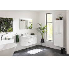 Salle de bain moderne et lumineuse avec meuble sous vasque, miroir éclairé, armoire haute suspendue et baignoire îlot.