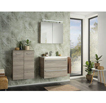 Salle de bains moderne avec meuble sous-vasque aspect bois, armoire de toilette, meuble suspendu et papier peint à motif de palmes.