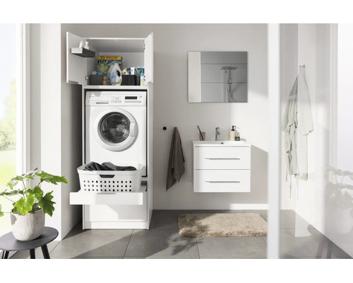 Salle de bains moderne et lumineuse avec meuble pour lave-linge blanc, meuble sous lavabo, miroir et plante verte.