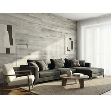 Salon moderne avec revêtement mural en aspect bois clair, canapé d'angle gris, table basse et tapis. Atmosphère lumineuse et organisée.