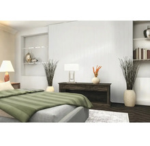 Chambre moderne avec lambris blanc, buffet sombre et lampes de table. Au premier plan, un lit avec du linge de lit à rayures vertes.