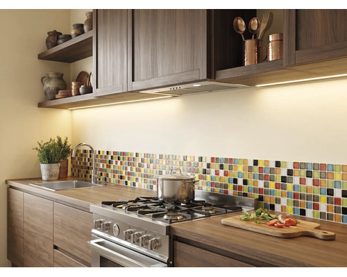 Cuisine moderne avec meubles en bois foncé, éclairage sous placard, cuisinière en acier inoxydable et crédence mosaïque sur plan de travail en bois.