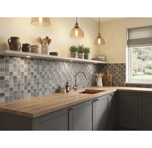 Cuisine moderne et lumineuse avec carrelage en mosaïque grise, plan de travail en bois, évier avec robinet en cuivre et suspensions en verre.