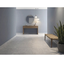 Couloir moderne avec de grands carreaux de sol aspect pierre, murs bleus, console en bois avec miroir et un banc.