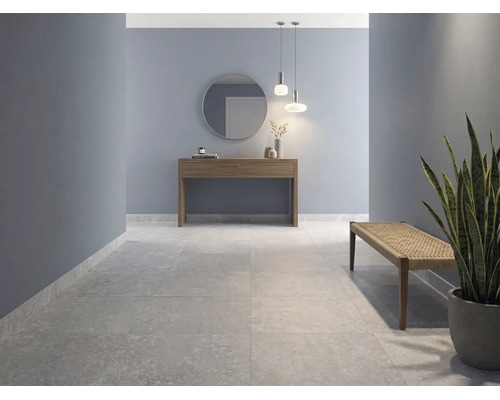 Couloir moderne avec de grands carreaux de sol aspect pierre, murs bleus, console en bois avec miroir et un banc.