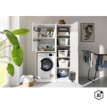 Armoire pour lave-linge et armoire d'appoint blanches dans la buanderie avec lave-linge, paniers, fer à repasser et lessive. (Image AI modified or generated)