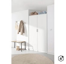 Entrée lumineuse avec une grande armoire blanche à deux portes, un banc de vestiaire en bois avec piètement en métal et un tapis rond. (Image AI modified or generated)
