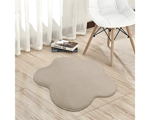 Beigefarbener Plüschteppich in Blumenform auf hellem Holzboden neben einem weißen Stuhl und Vorhängen in einem hellen Zimmer.