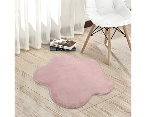 Tapis rose en forme de fleur à texture douce sur un parquet clair à côté d'une chaise.