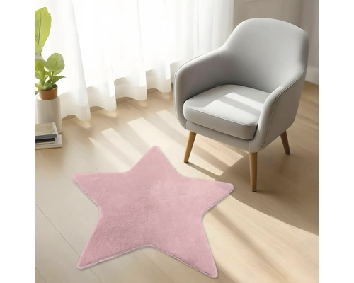 Rosa sternförmiger Plüschteppich auf einem Holzfußboden neben einem modernen Sessel in einem hellen Zimmer.