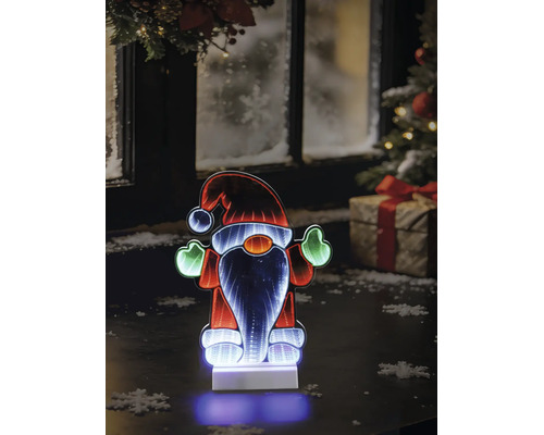 Gnome de Noël LED avec effet miroir infini sur une table devant une fenêtre hivernale avec sapin et cadeau.