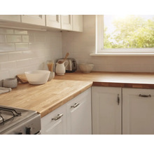 Cuisine lumineuse avec plan de travail en bois massif, meubles blancs et carrelage métro blanc. Comprend une fenêtre, un grille-pain et des bols.