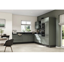 Cuisine moderne en L avec façades vert sauge, plan de travail sombre, four encastré et micro-ondes dans un design lumineux.