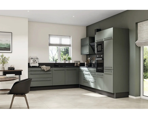 Cuisine moderne en L avec façades vert sauge, plan de travail sombre, four encastré et micro-ondes dans un design lumineux.