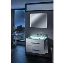 Meuble sous-vasque moderne blanc éclairé avec plan de toilette en verre et miroir dans une salle de bains avec vue sur la ville la nuit.
