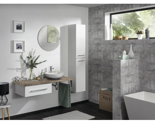Salle de bains moderne avec meuble sous-vasque suspendu, armoire haute blanche, miroir rond et baignoire îlot devant des murs carrelés gris.