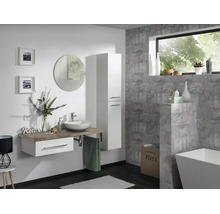 Modernes Badezimmer mit hängendem Waschtisch, weißem Hochschrank, rundem Spiegel und freistehender Badewanne vor grauen Fliesenwänden.