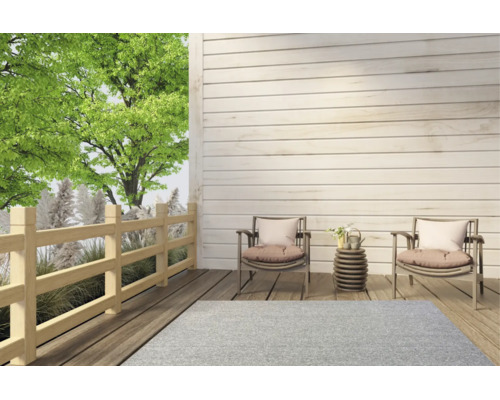 Terrasse moderne en bois avec deux fauteuils, une table d'appoint, un tapis d'extérieur gris clair, une balustrade en bois et un arbre vert.
