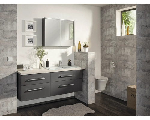 Salle de bain moderne avec meuble sous-vasque gris foncé, lavabo blanc, armoire de toilette et carrelage mural gris effet pierre.