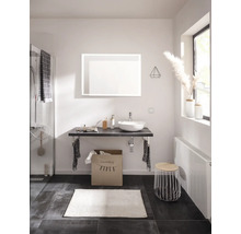 Salle de bains moderne avec vasque à poser, miroir lumineux, plan de toilette, sac à linge, radiateur et accessoires de salle de bains.