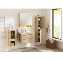 Ensemble de meubles de salle de bains clair aspect bois avec meuble sous vasque, armoire de toilette et deux colonnes dans une salle de bains.