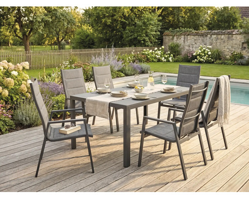 Ensemble de jardin avec table rectangulaire et six chaises à accoudoirs sur une terrasse en bois au bord d'une piscine dans un jardin aménagé.