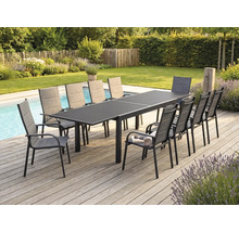 Ensemble repas de jardin avec grande table extensible gris foncé et dix fauteuils en tissu sur une terrasse en bois au bord d'une piscine.