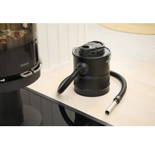 Aspirateur à cendres électrique avec réservoir en métal et tuyau d aspiration flexible dans une pièce lumineuse à côté d une cheminée.