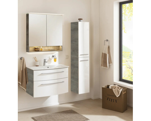 Ensemble de salle de bain moderne dans une pièce lumineuse : meuble sous vasque blanc, armoire de toilette éclairée et colonne aspect bois.