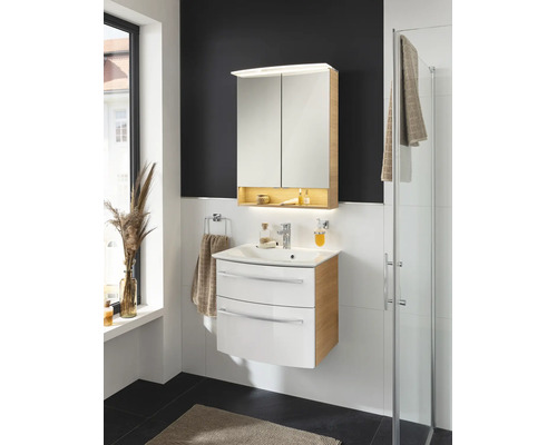 Ensemble de salle de bains avec un meuble sous-lavabo blanc et bois et une armoire de toilette assortie avec éclairage intégré.