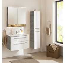 Ensemble de salle de bain moderne dans une pièce lumineuse : meuble sous vasque blanc, armoire de toilette éclairée et colonne aspect bois.