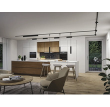 Moderne, helle Küche mit Kochinsel, Barhockern und schwarzem Schienensystem. Holzelemente, Einbaugeräte und Wohnbereich im Vordergrund.