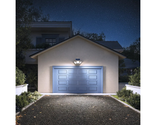 Solar-LED-Aussenstrahler mit Bewegungsmelder über einem Garagentor, der die Einfahrt bei Nacht hell beleuchtet.
