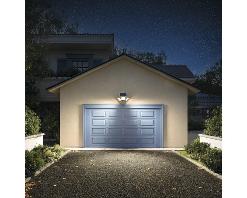 Solar-LED-Aussenleuchte mit drei verstellbaren Köpfen über einem Garagentor montiert, beleuchtet eine Einfahrt bei Nacht.