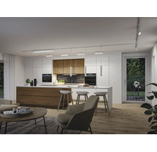 Moderne offene Küche mit Insel, Holzschränken, Schienensystem an der Decke und Pendelleuchten über der Theke. Heller, geräumiger Innenraum.