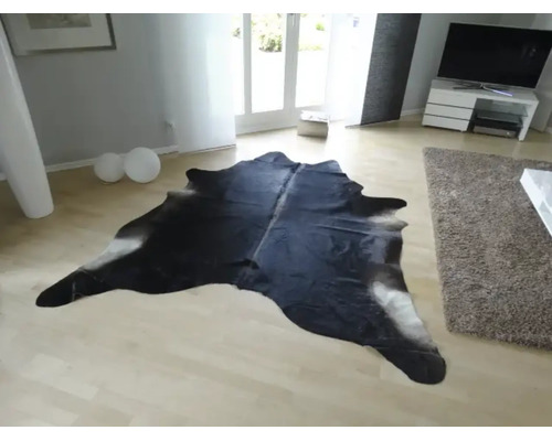 Kuhfell-Teppich in einem hellen, modernen Wohnzimmer auf hellem Holzboden.