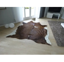 Tapis en peau de vache de forme naturelle dans un salon moderne et lumineux avec un parquet clair.