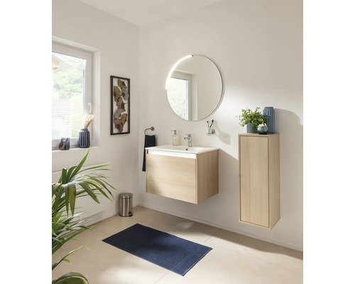Salle de bain moderne et lumineuse avec meuble sous-lavabo en bois, lavabo en céramique, miroir rond éclairé et armoire haute assortie.