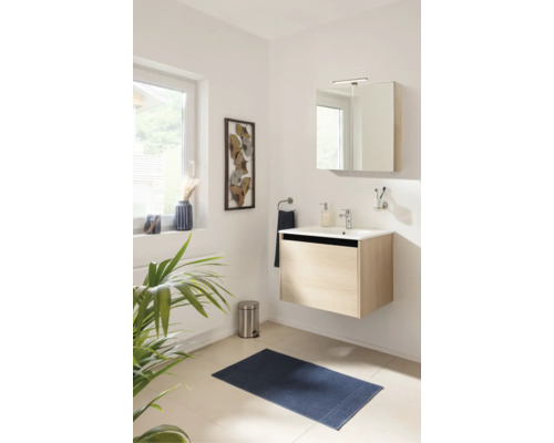 Salle de bains moderne et lumineuse avec meuble sous-vasque suspendu aspect bois, lavabo en céramique blanche et armoire de toilette éclairée.
