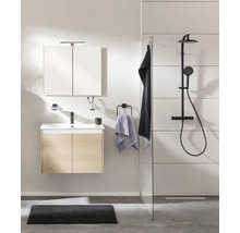 Modernes Badezimmer mit Waschtischunterschrank in Eichenoptik, Spiegelschrank und schwarzer Duscharmatur hinter einer Glaswand.
