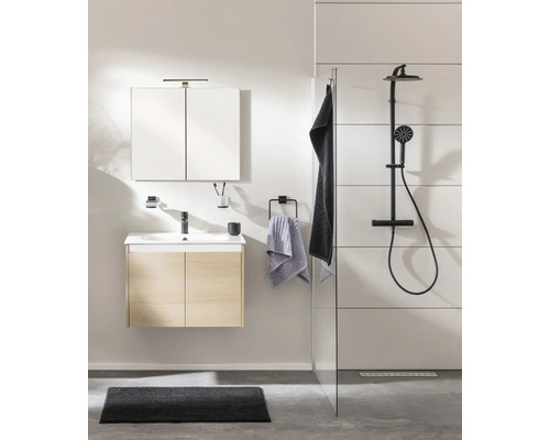 Modernes Badezimmer mit Waschtischunterschrank in Eichenoptik, Spiegelschrank und schwarzer Duscharmatur hinter einer Glaswand.