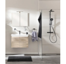 Salle de bains moderne avec meuble sous lavabo aspect bois, lavabo blanc, robinetterie noire, armoire de toilette et système de douche noir.