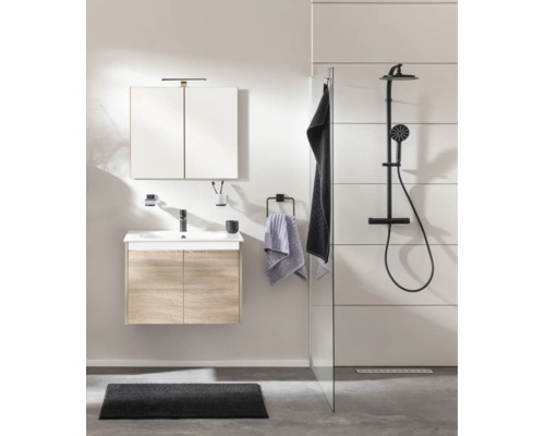 Salle de bains moderne avec meuble sous lavabo aspect bois, lavabo blanc, robinetterie noire, armoire de toilette et système de douche noir.
