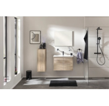 Ensemble de salle de bain moderne aspect chêne avec meuble sous-vasque, miroir, colonne et système de douche noir dans une pièce lumineuse.