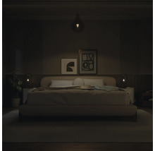 Chambre à coucher moderne avec lit rembourré, tableaux abstraits et éclairage par suspension et lampes de chevet.