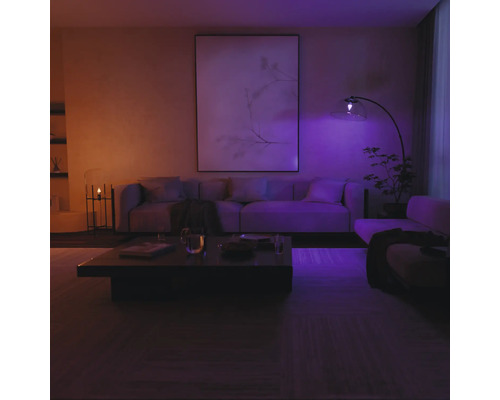 Salon moderne avec canapé, table basse et lampadaire, éclairé par un éclairage intelligent.