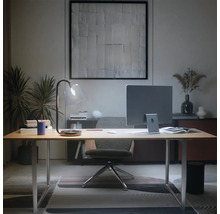 Bureau à domicile moderne avec bureau en bois clair, moniteur, lampe en verre et chaise ergonomique dans une ambiance ordonnée.